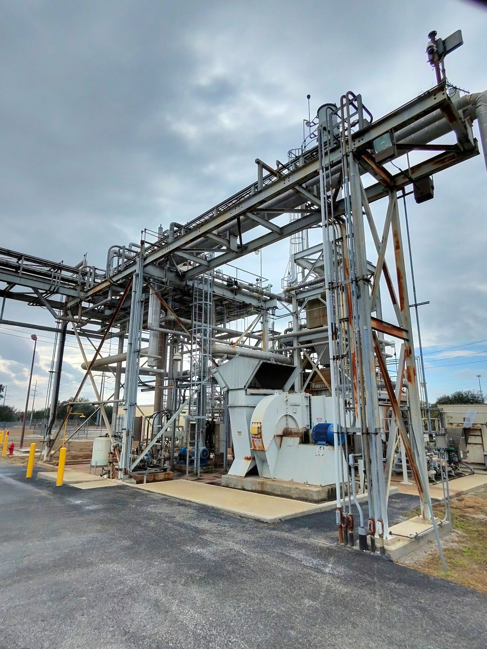 Industrial metal conveyor structure at an outdoor facility under a cloudy sky