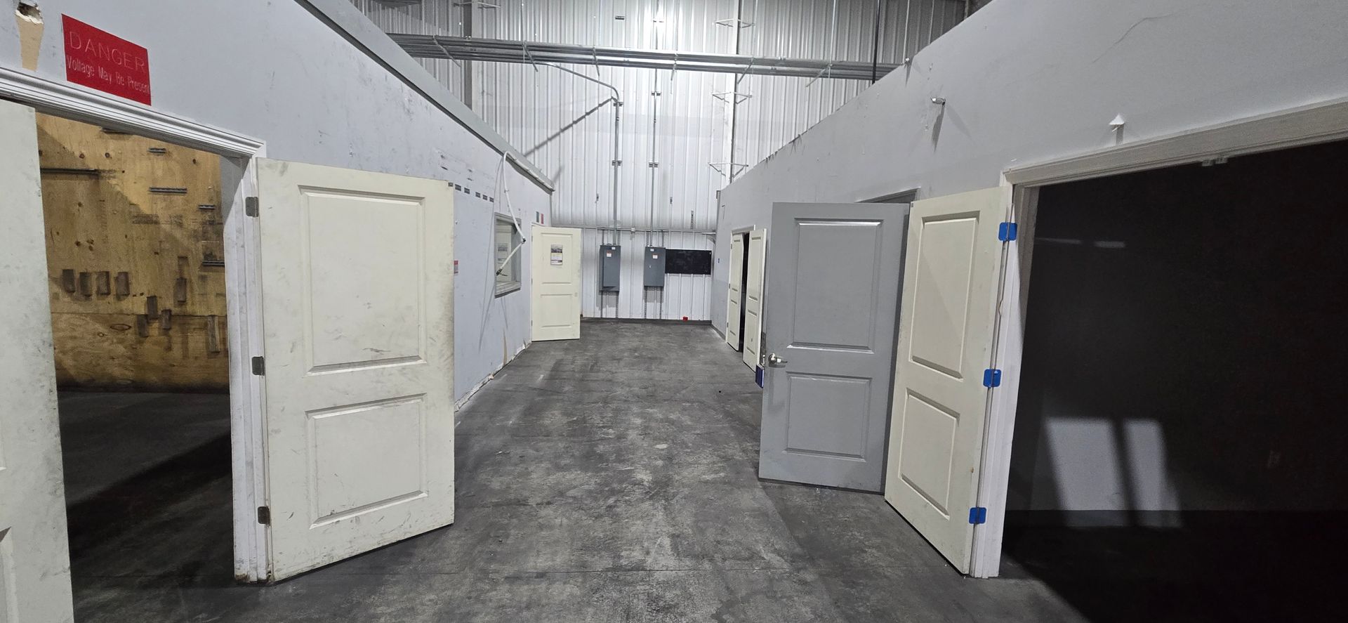 Open warehouse interior with several white doors standing open along both walls