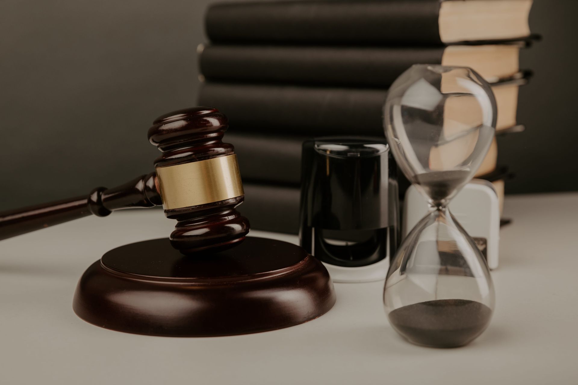 Law gavel, books, and hourglass on a desk, symbolizing justice and time