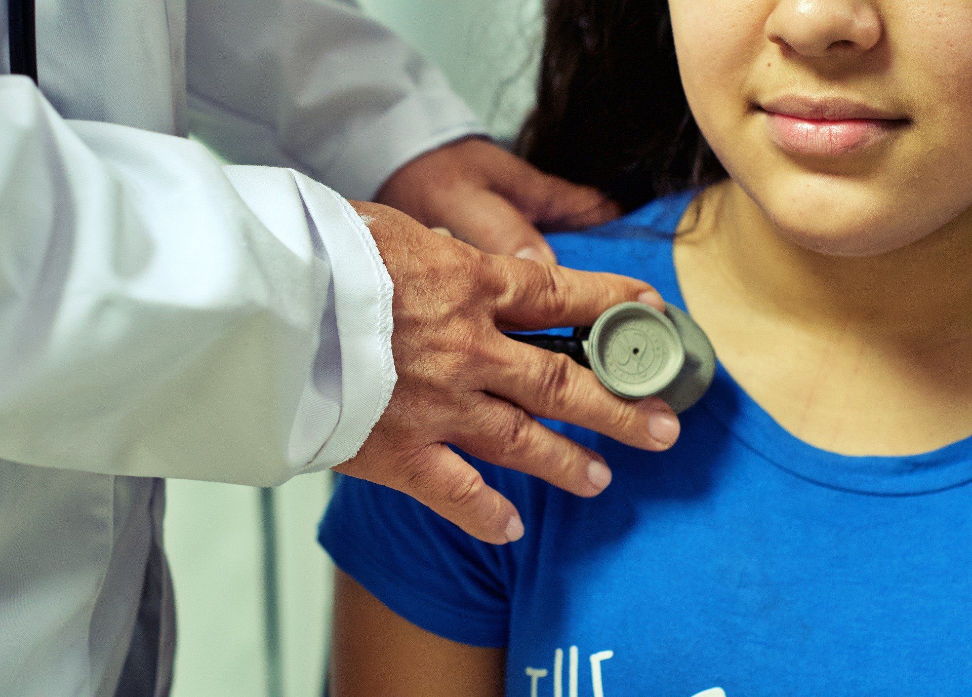 A doctor is listening to a woman's heart beat with a stethoscope