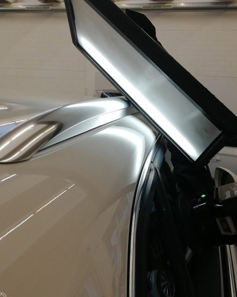 Primo piano di un'auto argentata con il portellone aperto in un garage, che mostra il tetto posteriore e il vano bagagli.