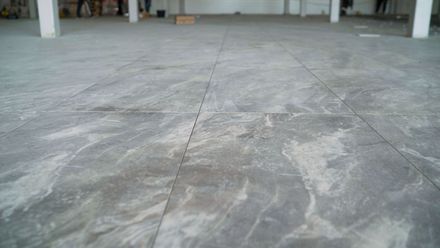 Empty concrete floor inside a warehouse or garage, with visible stains and seams.