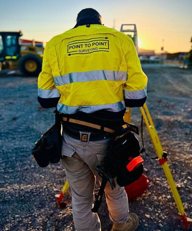 A Man in a Yellow Jacket is Standing Next to a Tripod — Point to Point Surveying In Tatura, VIC