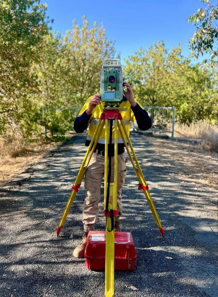 A Man is Standing With a Tripod — Point to Point Surveying In Tatura, VIC