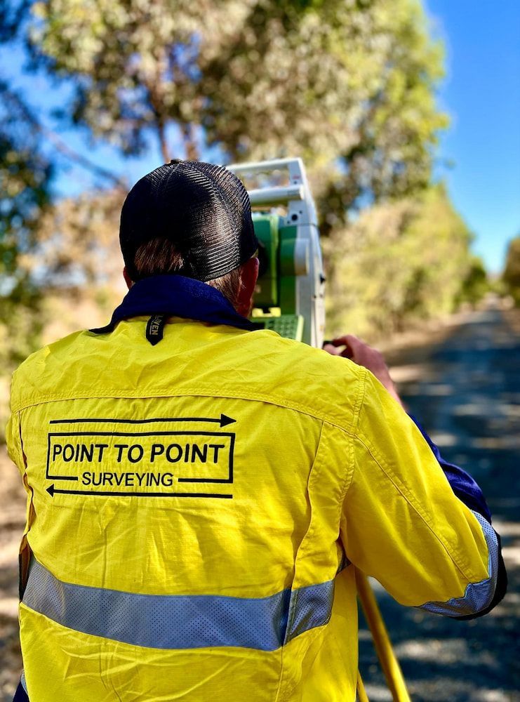 A Man in a Yellow Jacket is Surveying a Road — Point to Point Surveying In Tatura, VIC