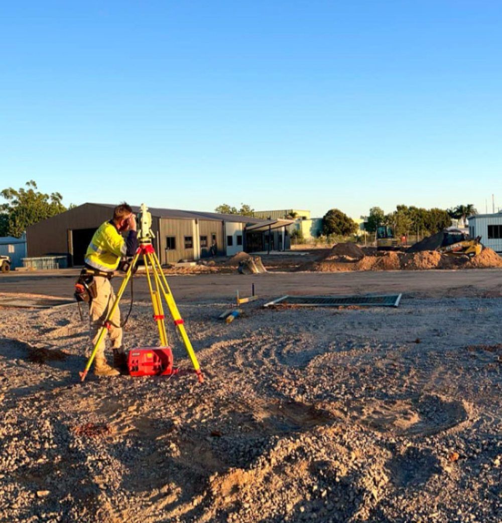 A Man Is Standing In The Dirt Using A Tripod To Take A Picture — Point to Point Surveying In Kyabram, VIC