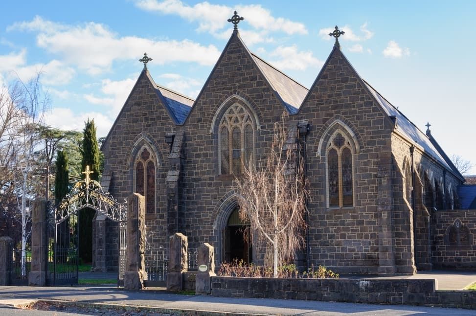 A Large Brick Church With A Cross On Top Of It — Point to Point Surveying In Tatura, VIC