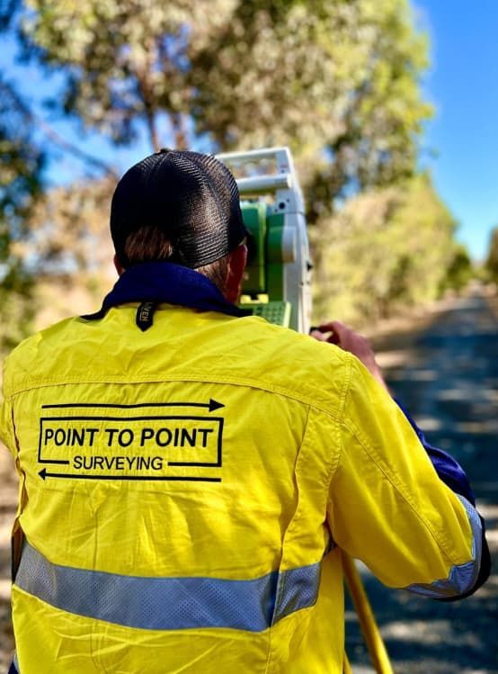 A Man In A Yellow Jacket Is Surveying A Road — Point to Point Surveying In Benalla, VIC