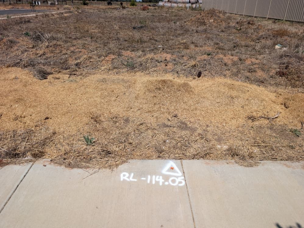 A White Triangle Is Painted On The Sidewalk In Front Of A Dirt Field — Point to Point Surveying In Cobram, VIC