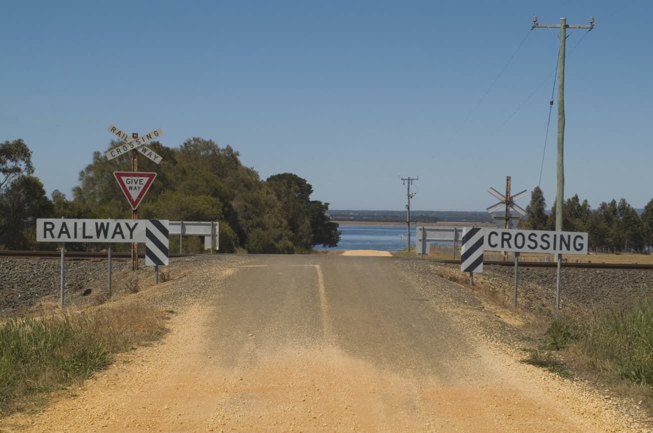 A Dirt Road With A Railway Crossing Sign On The Side Of It — Point to Point Surveying In Tatura, VIC