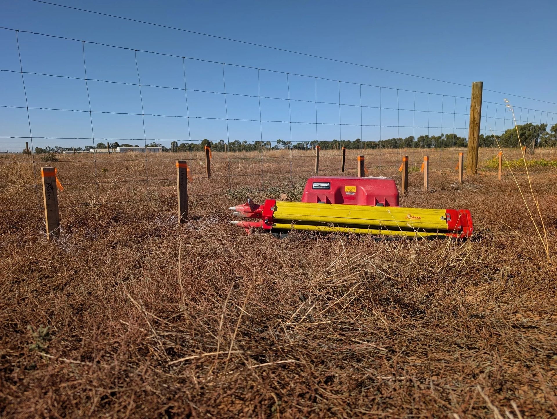 Construction Site With Surveying Equipment on a Tripod in the Foreground — Point to Point Surveying In Tatura, VIC