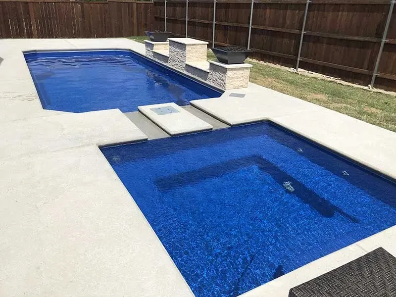Backyard with two blue pools, stepping stones, and a wooden fence
