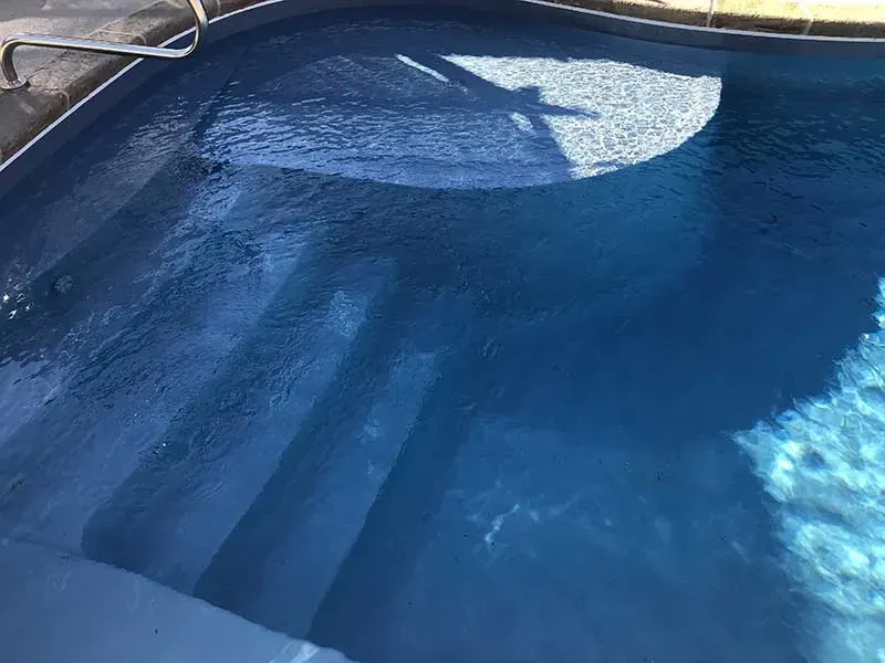 Blue swimming pool water with a floating white object near the edge
