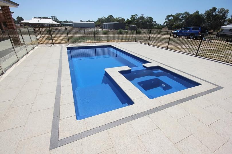 Backyard pool with a raised blue wheelchair-access ramp and stainless handrails