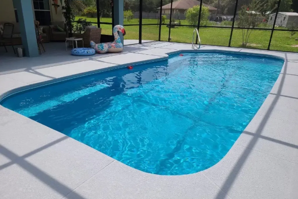 Backyard swimming pool with clear blue water and white patio