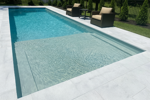 Modern rectangular swimming pool with clear blue water, white tile deck, and lounge chairs by a green lawn