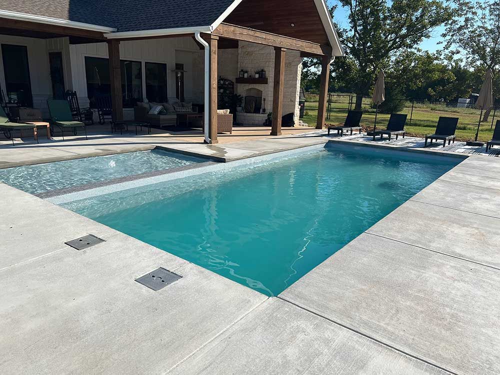 Backyard patio with a turquoise swimming pool beside a covered outdoor seating area