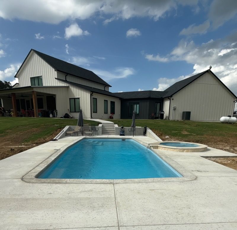 Modern house with a backyard swimming pool and spa under a cloudy sky
