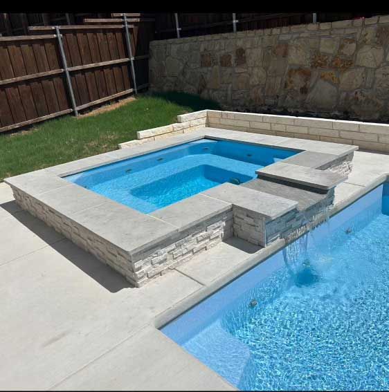 Modern backyard pool with raised spa, stone surround, and blue water