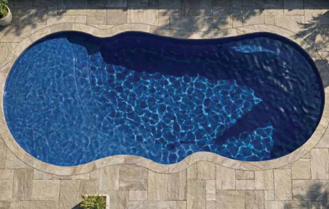 Blue kidney-shaped swimming pool surrounded by tan stone paving, viewed from above