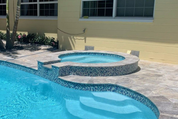 Backyard swimming pool with a raised circular spa and light blue water beside a house