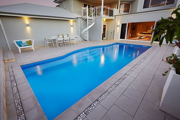 Indoor courtyard with a blue swimming pool, white lounge chairs, and a staircase