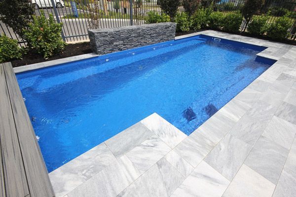 Modern rectangular backyard pool with blue water and gray stone deck