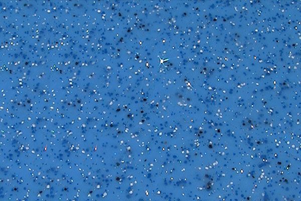 Blue field covered with many tiny scattered specks and a small white mark near the center