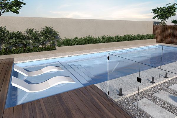 Modern backyard pool with shallow ledge loungers, glass fence, wood deck, and landscaped privacy wall