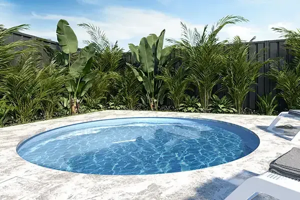 Small round blue swimming pool surrounded by tropical plants and white lounge chairs under bright sun