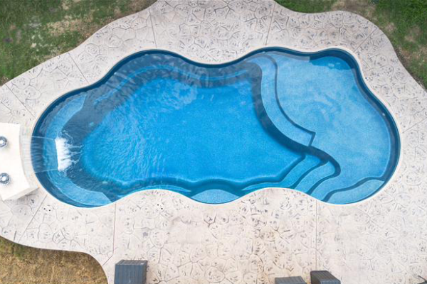 Top-down view of a blue kidney-shaped swimming pool with a light stone deck.