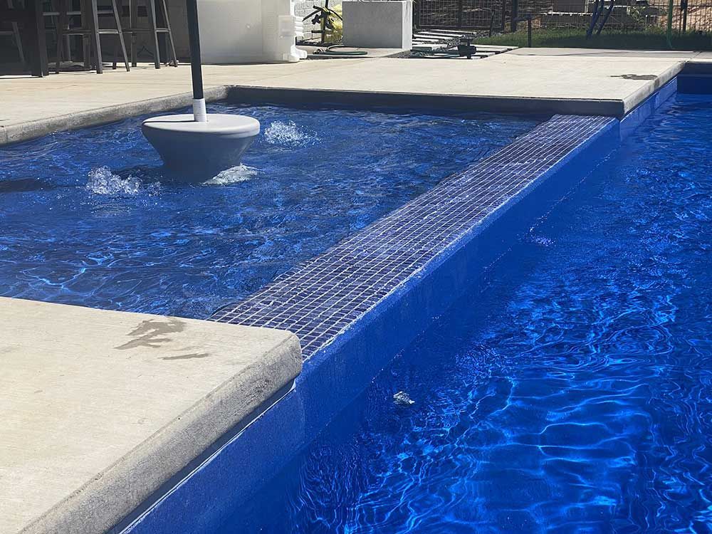 Blue resort-style swimming pool with a narrow water feature and concrete walkways
