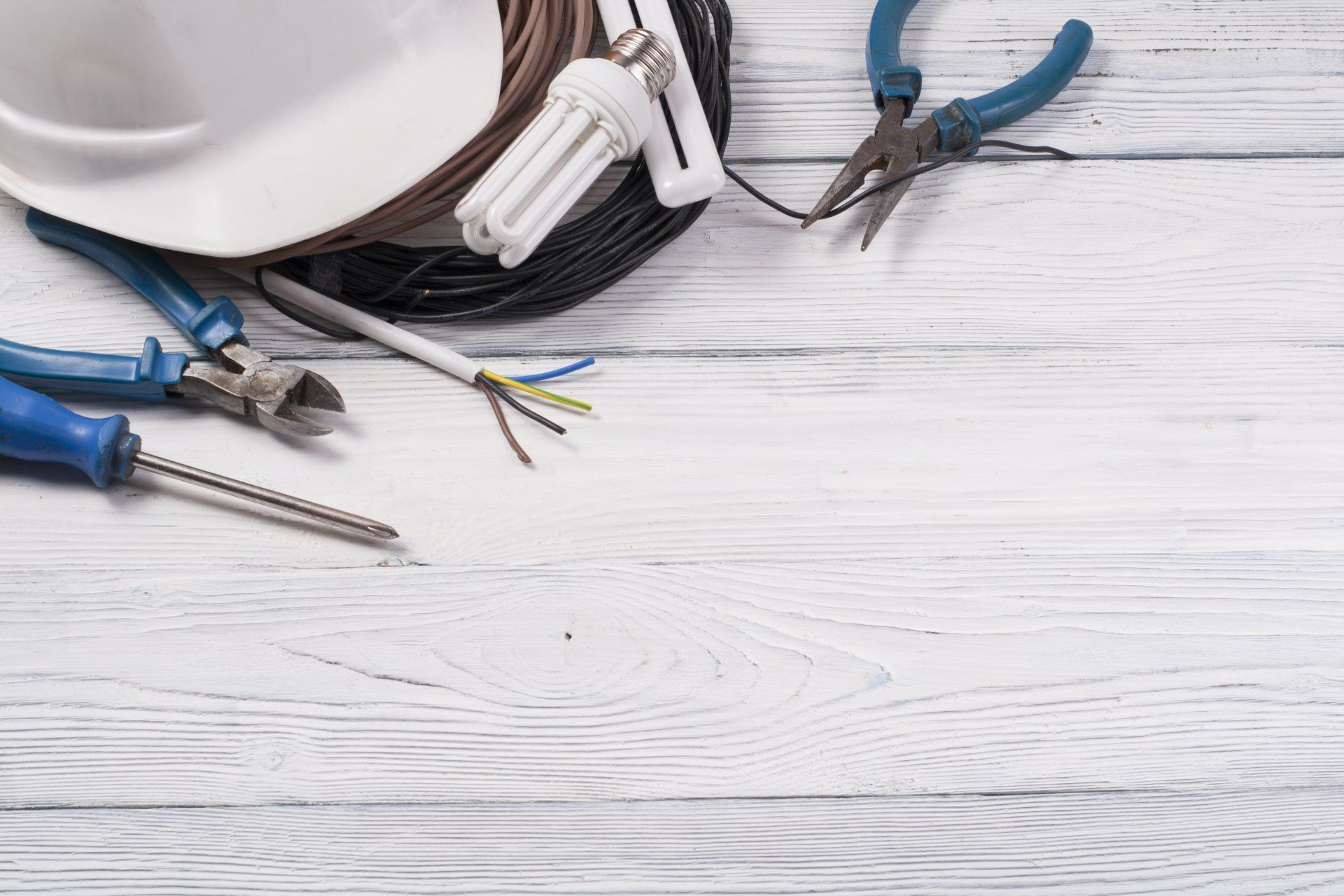 Pinces et tournevis d'électricien disposés sur un plan de travail en bois clair