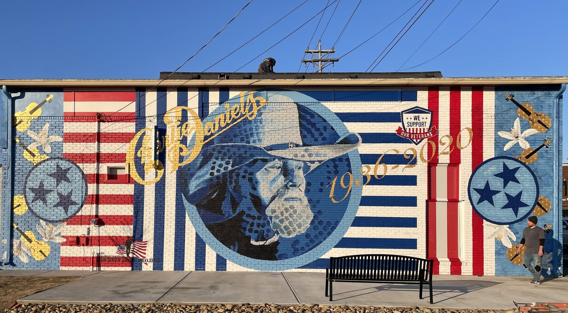 A large mural on the side of a building with a bench in front of it