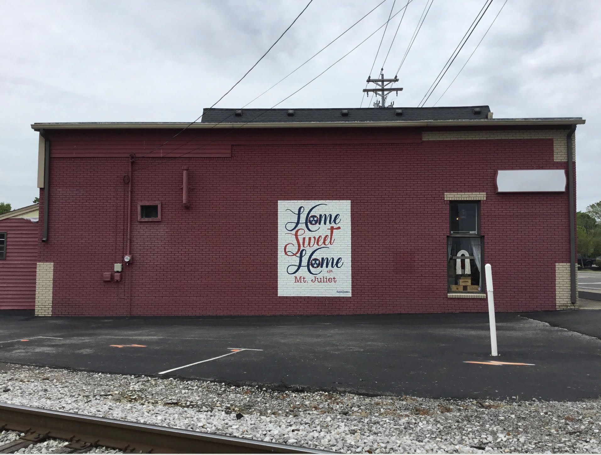 A sign on the side of a building says home sweet home