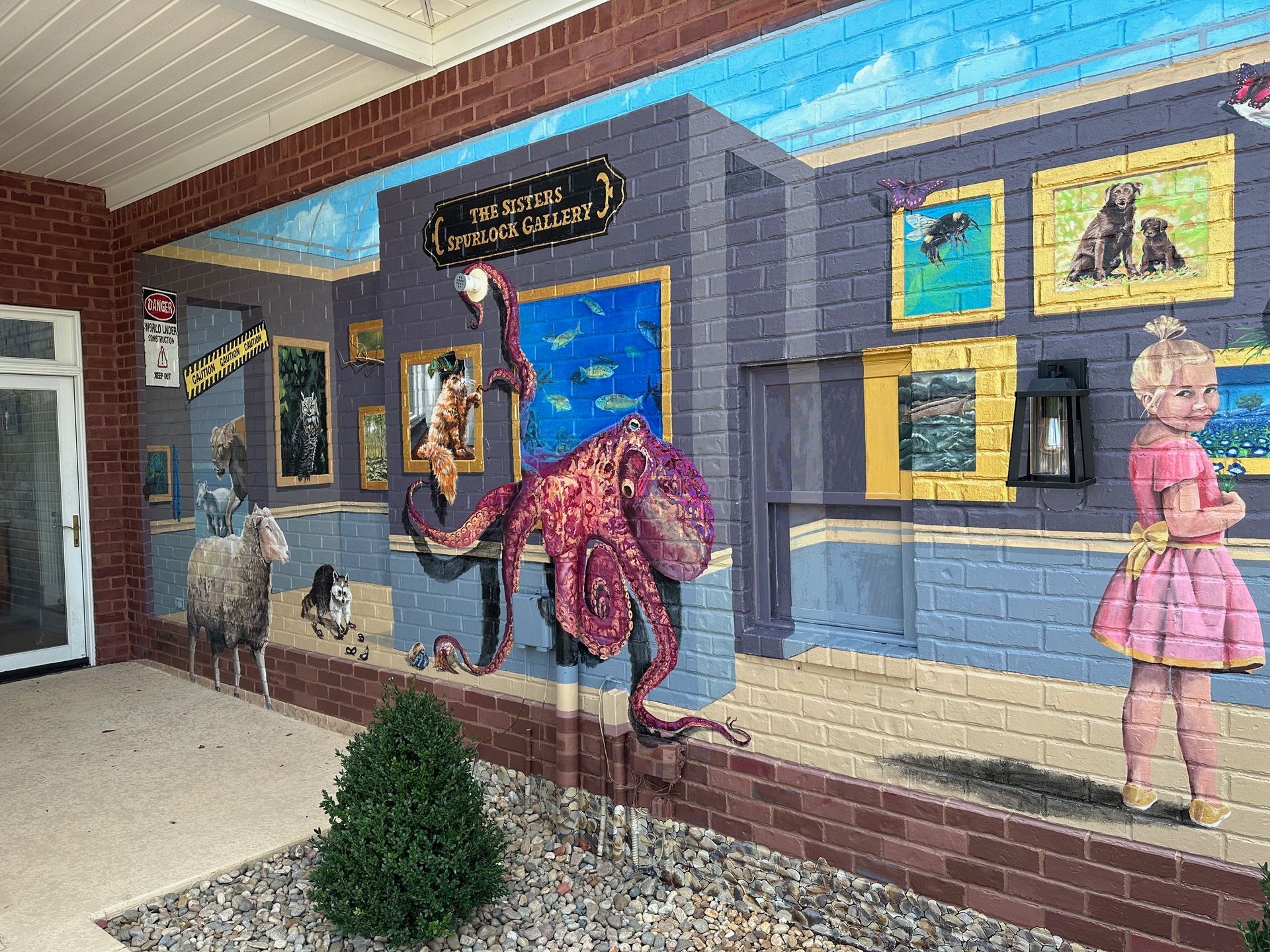 A mural of a girl standing next to an octopus on a brick wall.