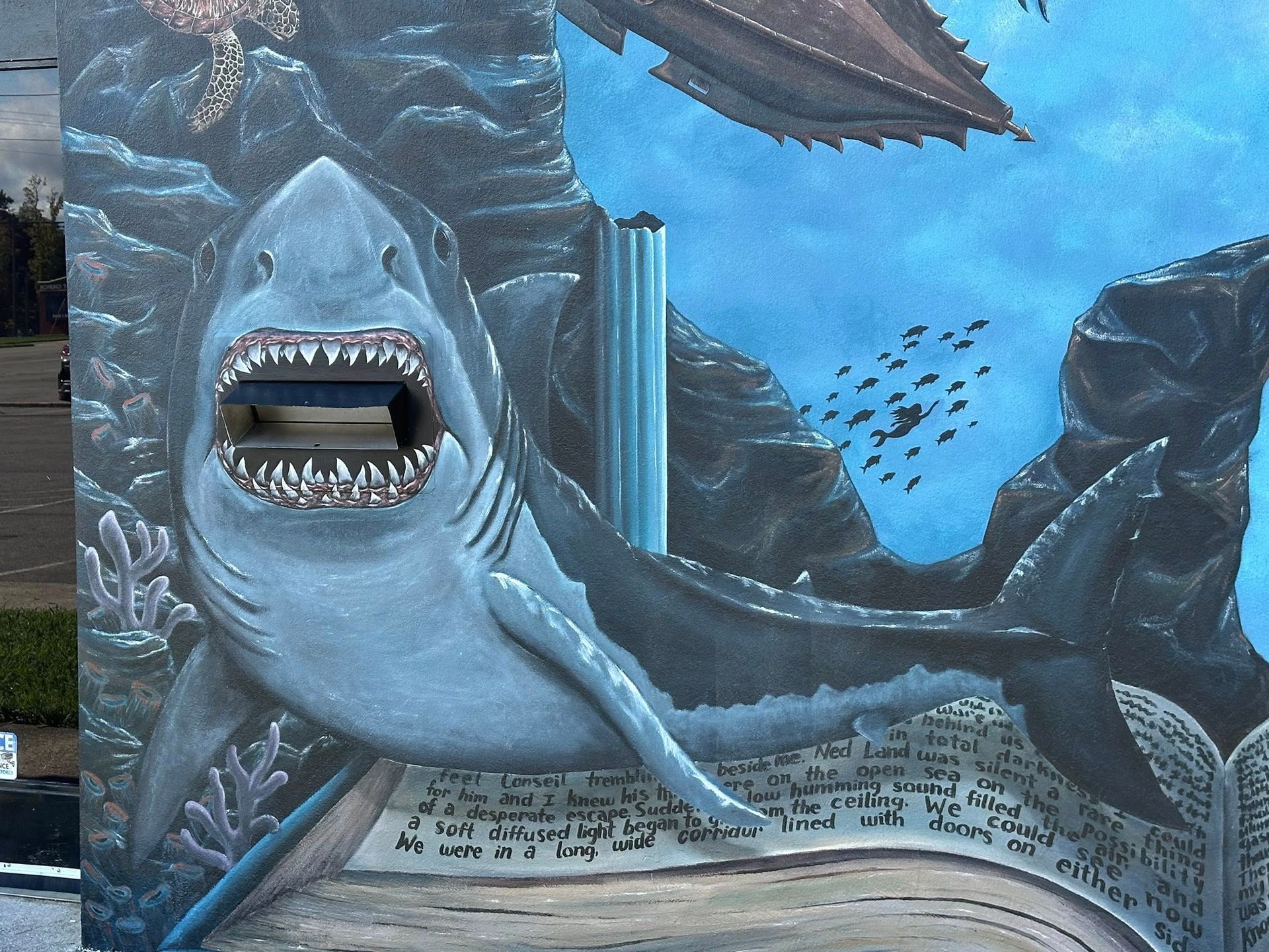 Mural of a shark with open mouth as a mail slot in an underwater scene with a book.