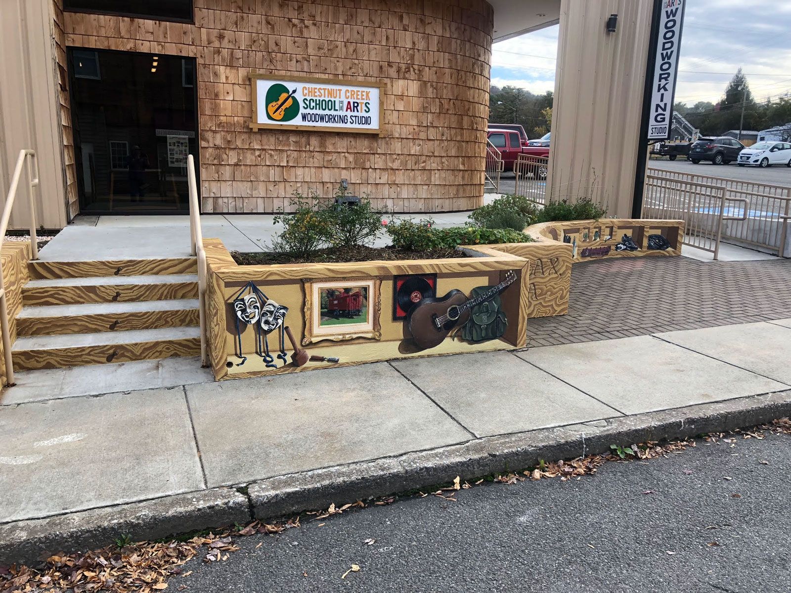 A building with stairs leading up to it and a planter on the sidewalk in front of it.