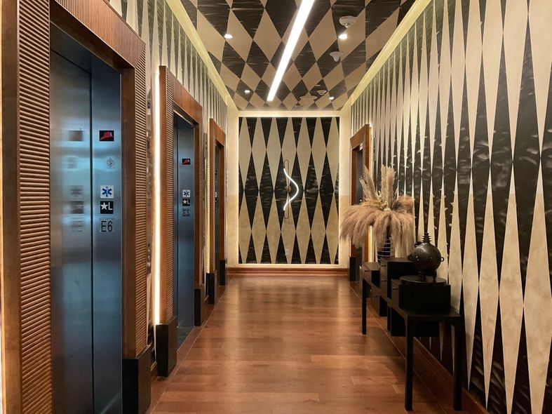 A long hallway with elevators and a checkered ceiling