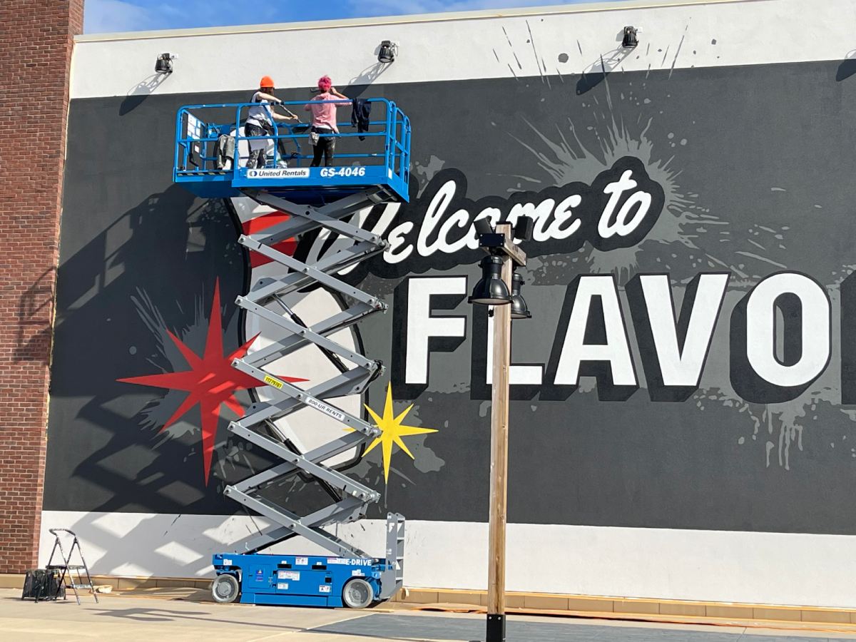 A mural is being painted on the side of a building that says welcome to flavo