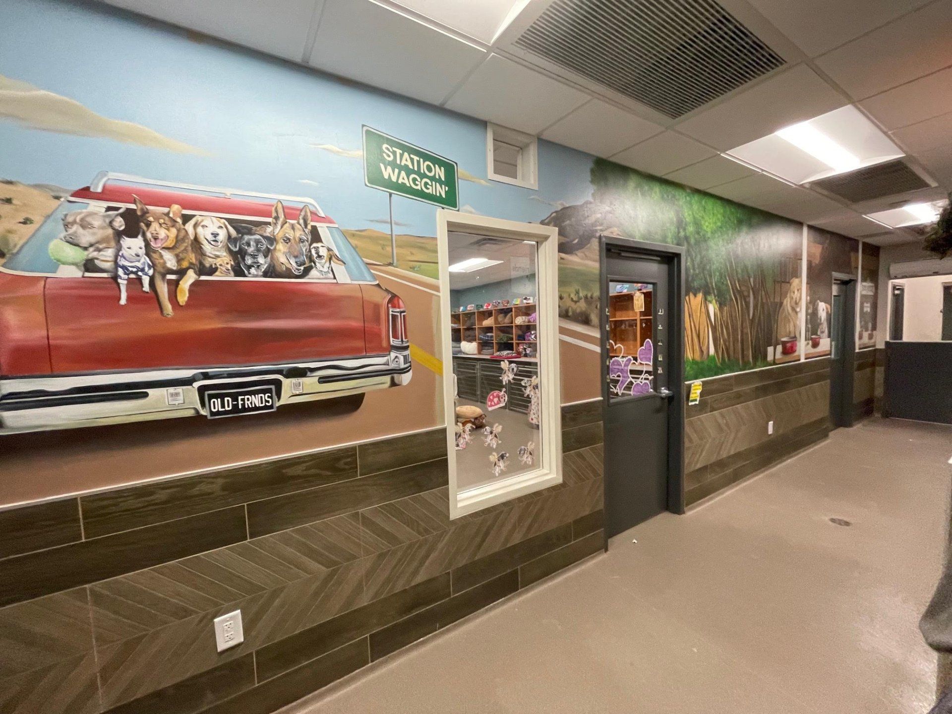 A hallway with a painting of a car with dogs in it.
