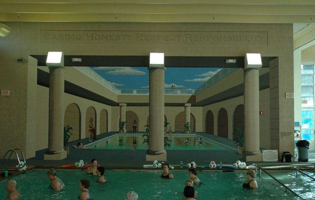A group of people are swimming in a large indoor pool.