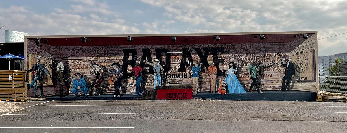 A large mural on the side of a building with people standing in front of it.
