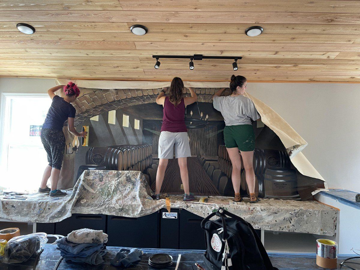 A group of people are working on a mural on a wall.