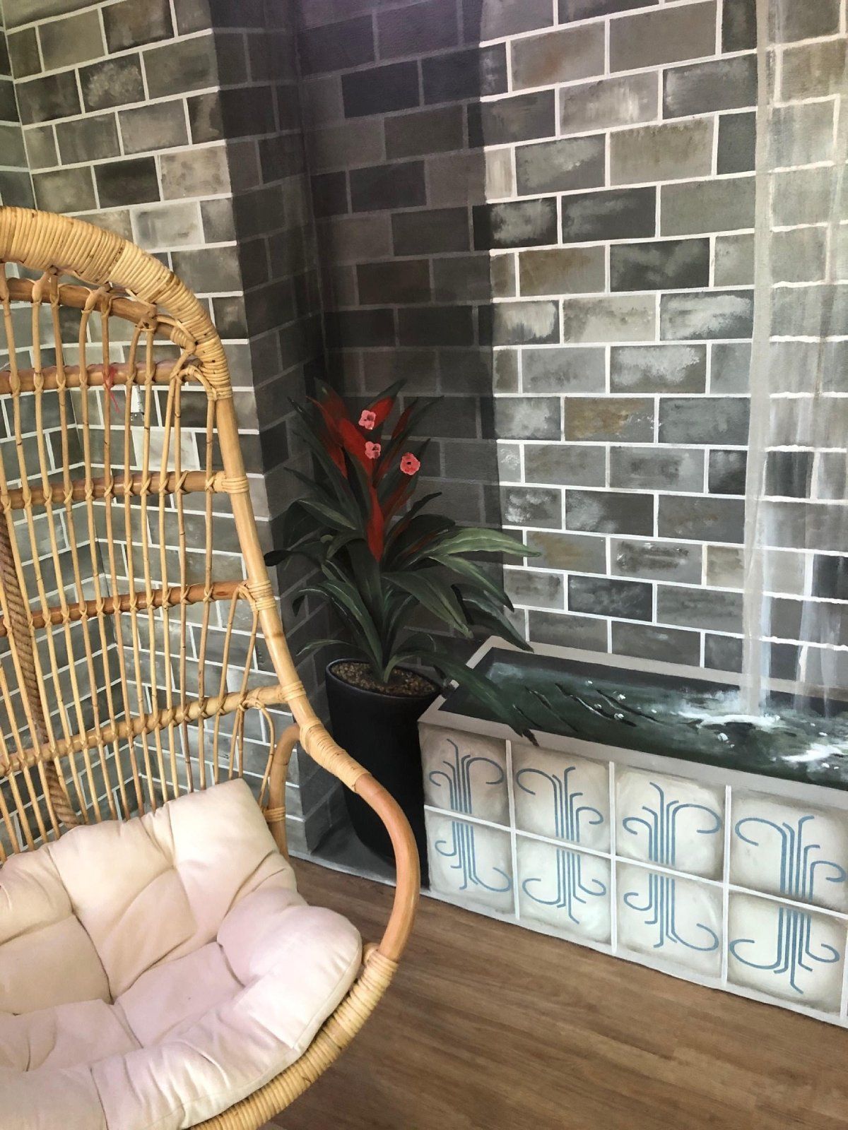 A wicker chair is sitting in front of a brick wall.