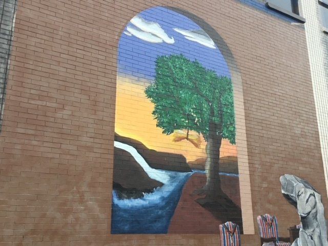 A painting of a tree and waterfall on a brick wall