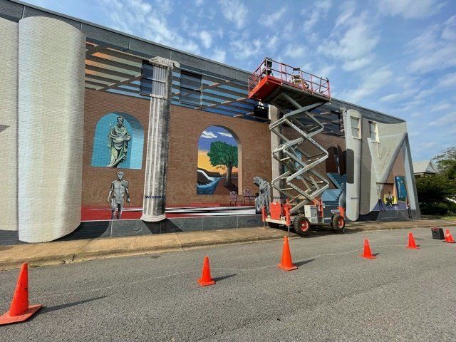 A mural is being painted on the side of a building