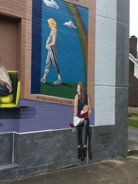 A painting of a woman holding a baby is on the side of a building