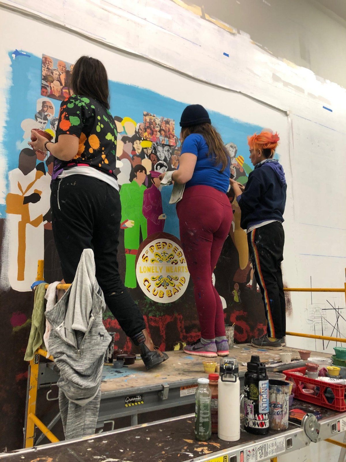A group of people are painting a mural on a wall.