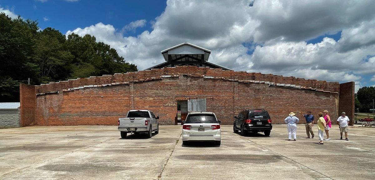A group of people are standing in front of a large brick building.